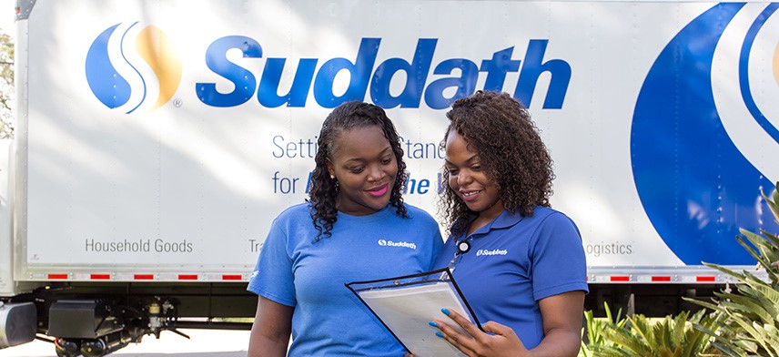 women moving crew standing in front of suddath moving truck