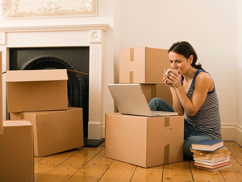 woman on laptop surrounded by moving boxes